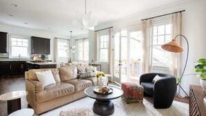 Un salon spacieux avec un canapé beige, une table basse ronde et un fauteuil noir.