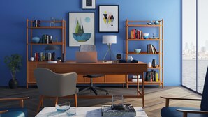 Un espace de bureau moderne comprenant un bureau, des chaises, des étagères et des œuvres d’art accrochées aux murs.