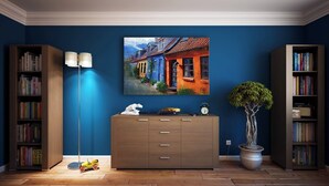 Une pièce avec un mur bleu, une commode en bois avec des tiroirs, un lampadaire, une plante en pot et deux étagères remplies de livres.