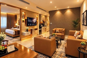 A hotel room with a bed, a sofa, a coffee table, a TV, and a reception desk. - Hotel Sakura Gold (Gurugram)