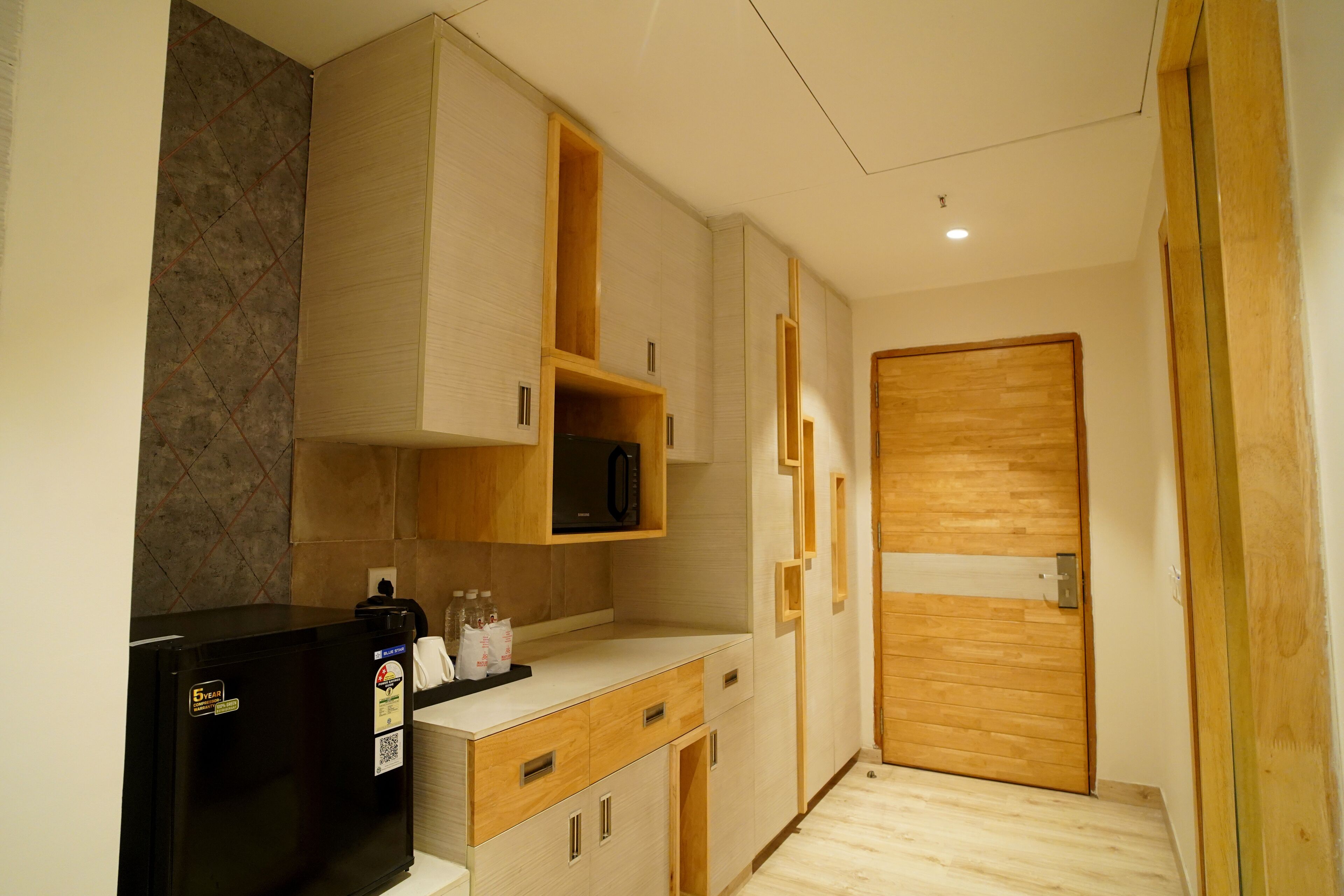 Una cocina compacta con refrigerador, microondas y armarios de madera.