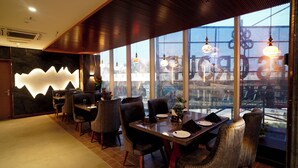 Ein Restaurant mit modernem Interieur, großen Fenstern und Blick auf die Stadt.