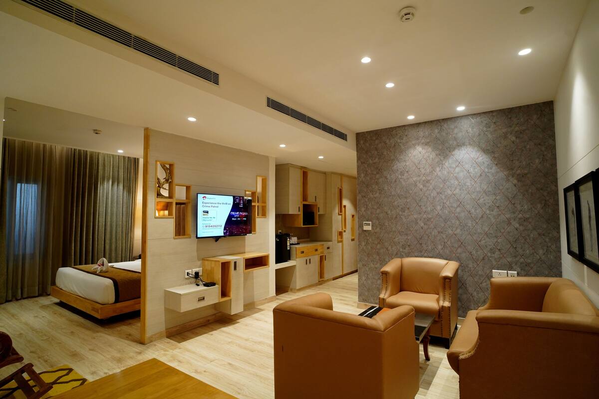 Une chambre d’hôtel moderne équipée d’un lit, d’un coin salon, d’une télévision et d’un plan de travail dans la cuisine.