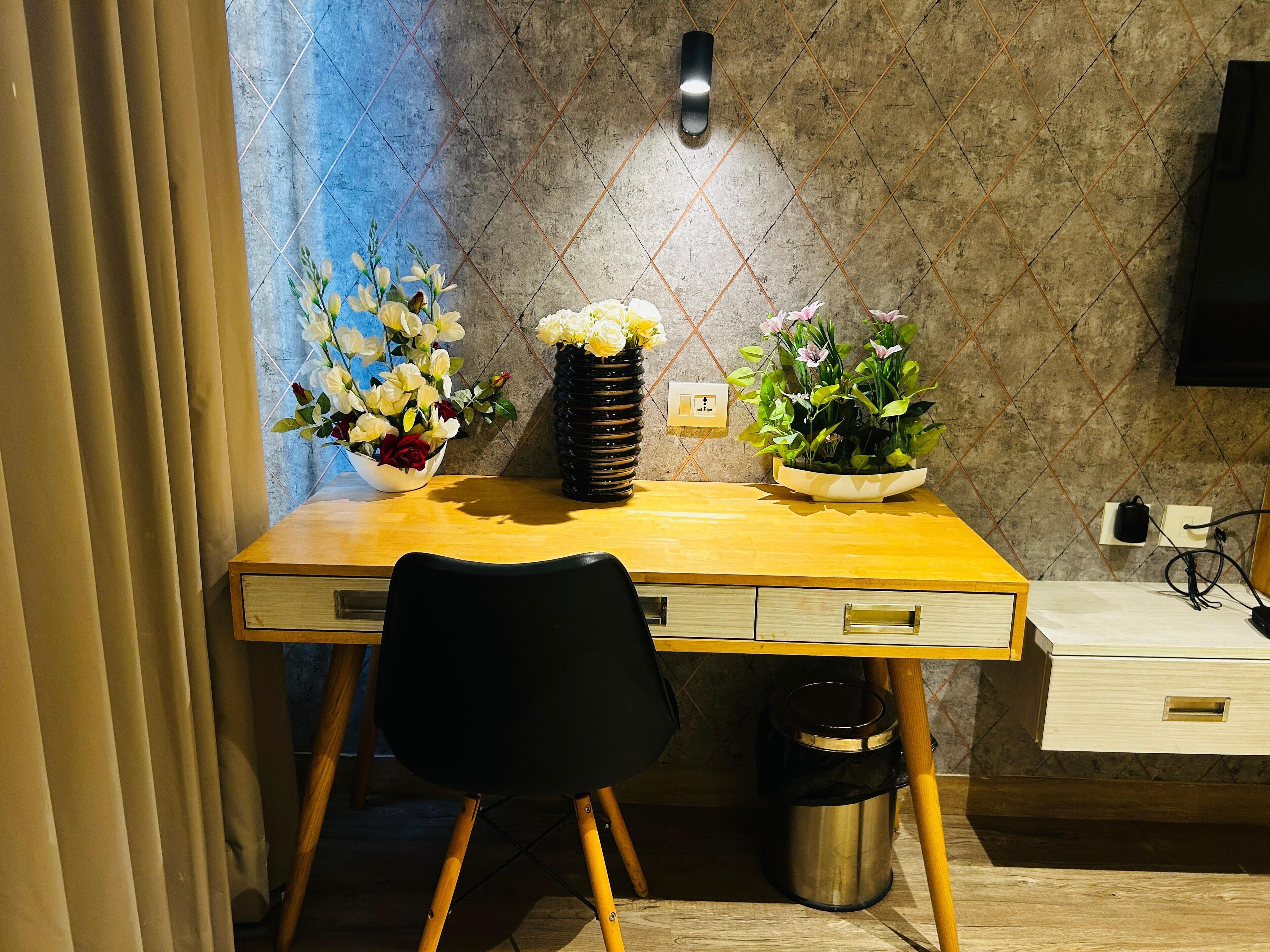 Una cocina moderna con un escritorio de madera, una silla negra y dos jarrones de flores sobre la encimera.