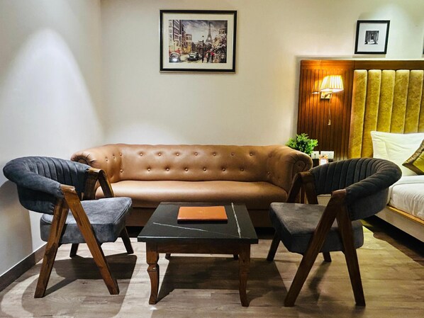 Una sala de estar moderna con un sofá marrón, dos sillones, una mesa de centro y un cabecero de madera con una lámpara.