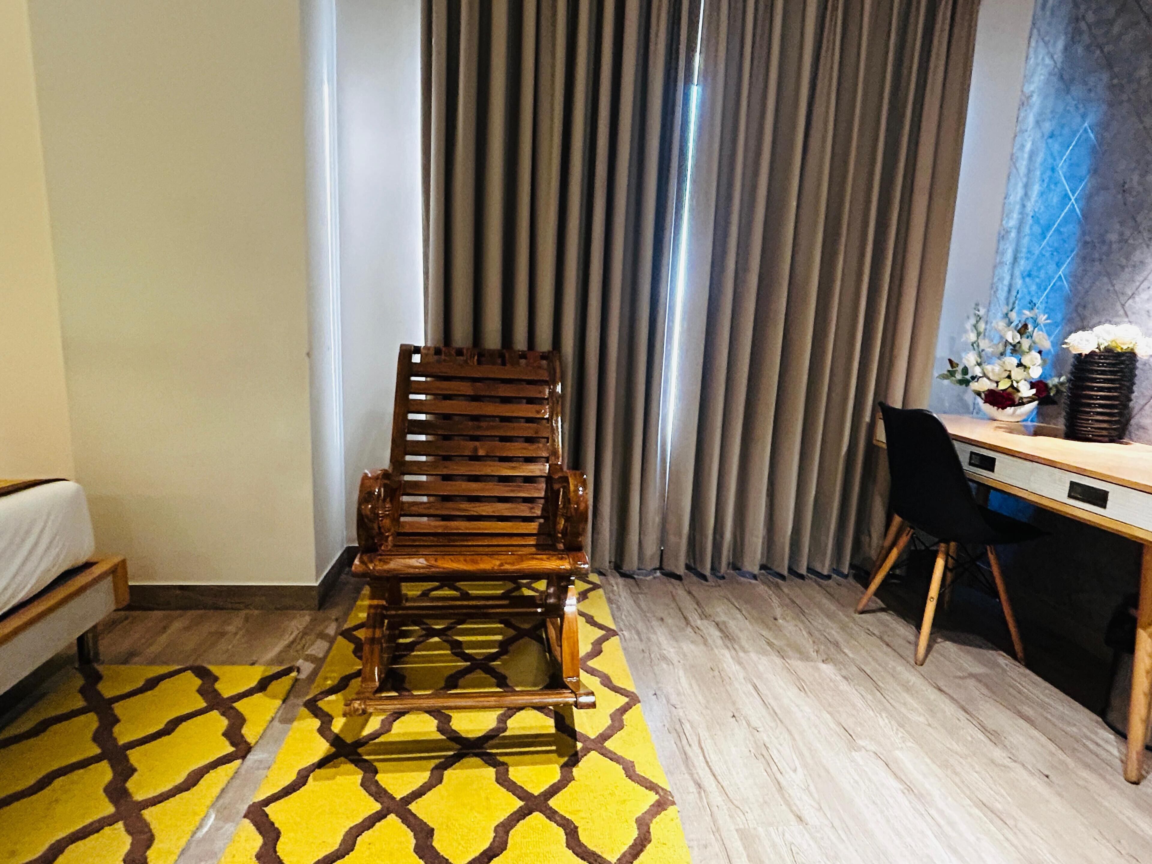 A hotel room with a wooden chair, a desk, and a bed.