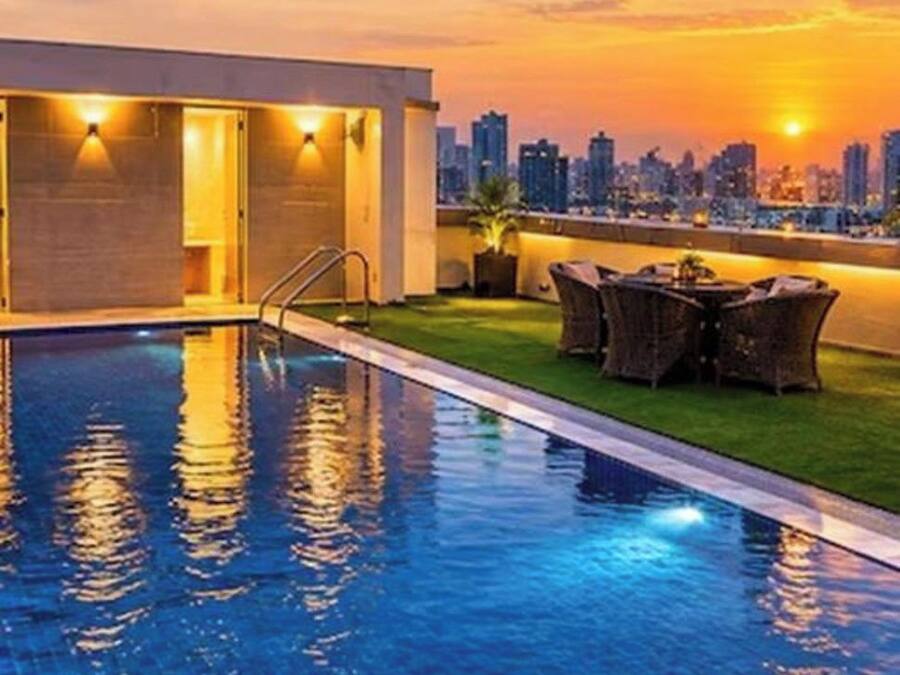 Una piscina con vista a un horizonte urbano al atardecer.