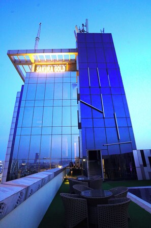 A modern building with a glass facade and a sign reading "SAKURA GOLD". - Hotel Sakura Gold (Gurugram)