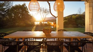 An outdoor dining area with a wooden table and black chairs, overlooking a scenic landscape with trees and mountains. - Luxury, self-catering Manor with 6 bedrooms, views of mountains & vineyards (Klapmuts)