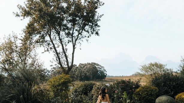 A woman standing at the edge of a swimming pool with a natural landscape in the background. - Luxury, self-catering Manor with 6 bedrooms, views of mountains & vineyards (Klapmuts)