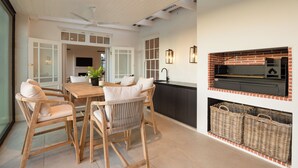 A modern kitchen with a brick fireplace, wooden dining table, and wicker baskets. - Luxury, self-catering Manor with 6 bedrooms, views of mountains & vineyards (Klapmuts)