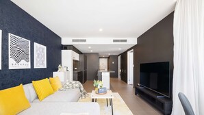 Un salon moderne avec un canapé, un téléviseur et des œuvres d’art accrochées au mur.