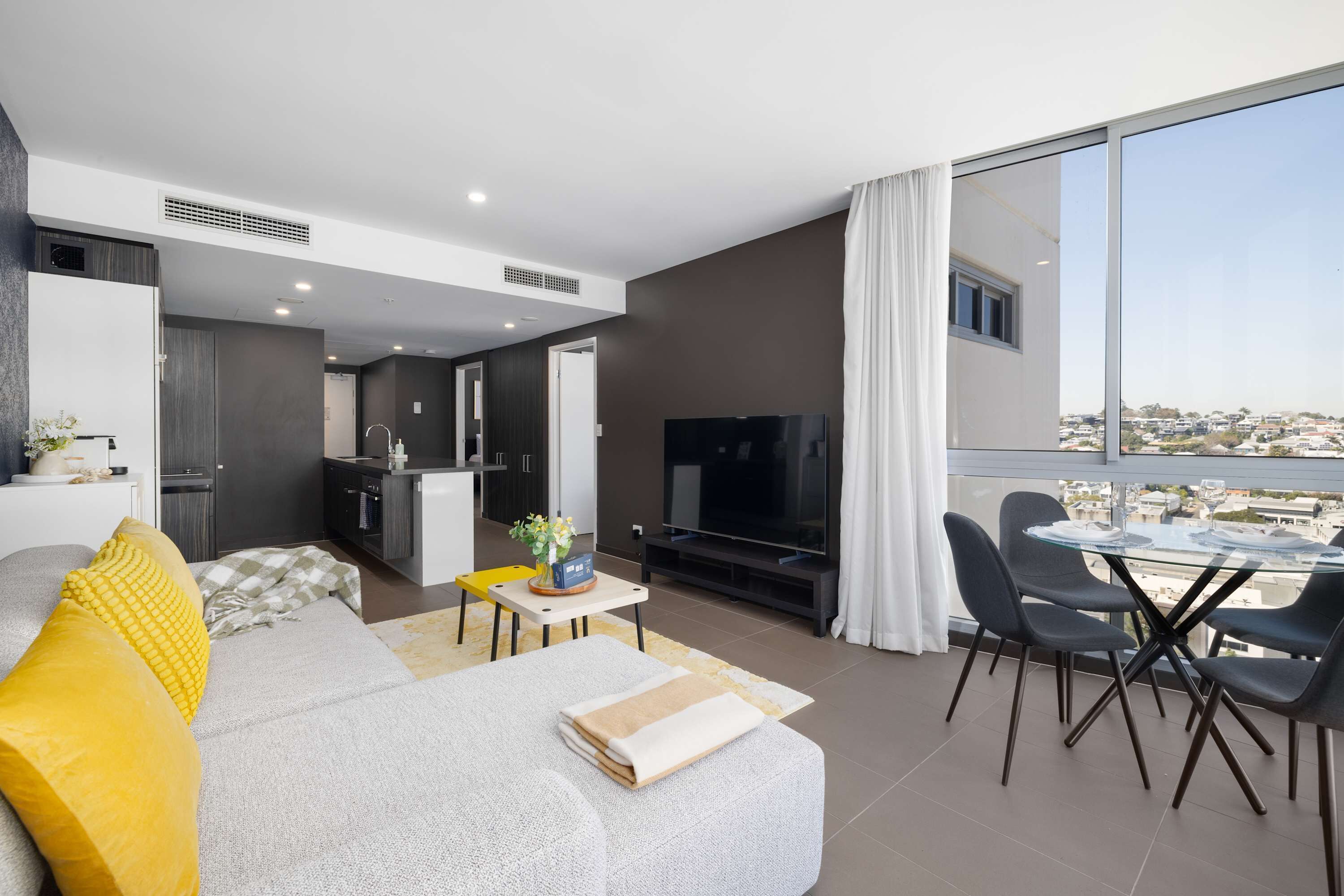 A modern living room with a sofa, TV, dining table, and chairs.