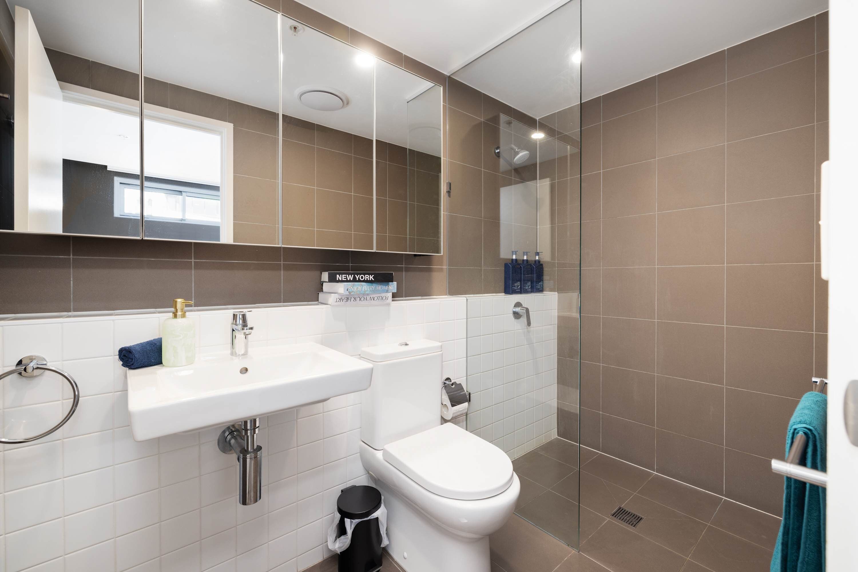 Un baño moderno con lavamanos, inodoro y ducha.