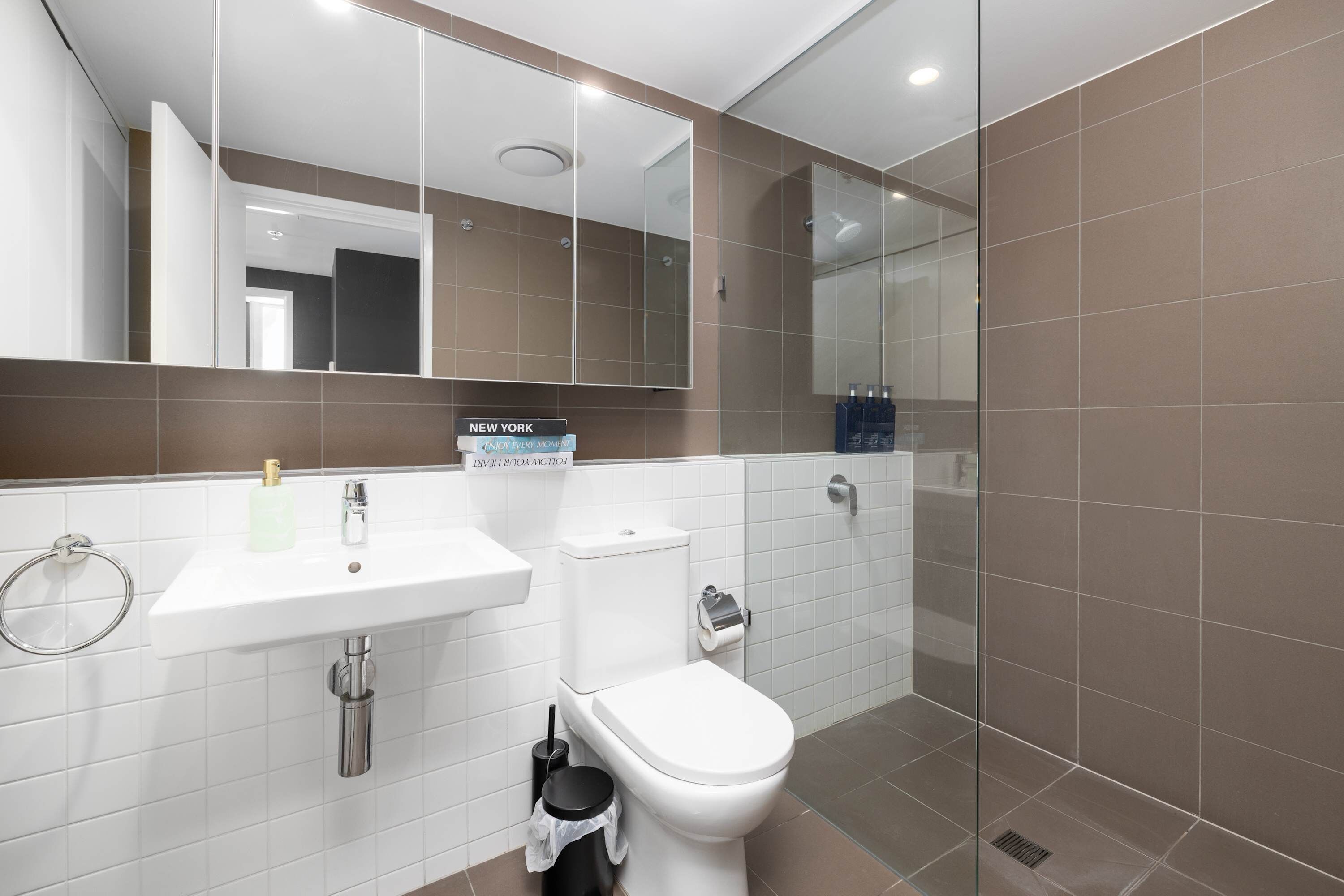Un baño moderno con lavamanos, inodoro y cabina de ducha de vidrio.