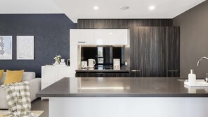 Une cuisine moderne dotée d’un îlot central, de meubles blancs et d’un mur d’accent de couleur foncée.