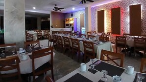 Ein Restaurant mit mehreren Tischen und Stühlen, Deckenventilatoren und einer Wand mit Muster.