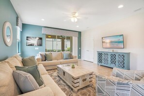 A living room with a sofa, coffee table, and a television.