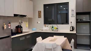 A modern kitchen with a dining area, featuring a built-in oven, a sink, and a window above the counter. - SeaView Country Garden 3BR2FREE By Natol (Johor Bahru)