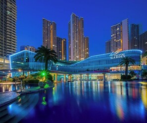 A modern hotel with a curved facade, a pool area, and high-rise buildings in the background. - SeaView Country Garden 3BR2FREE By Natol (Johor Bahru)