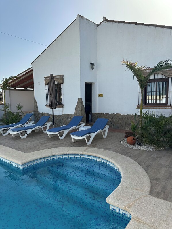 A pool area with lounge chairs and a building with a stone facade.