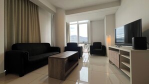 Una sala moderna con un sofá, sillones, una mesa de centro y un televisor.