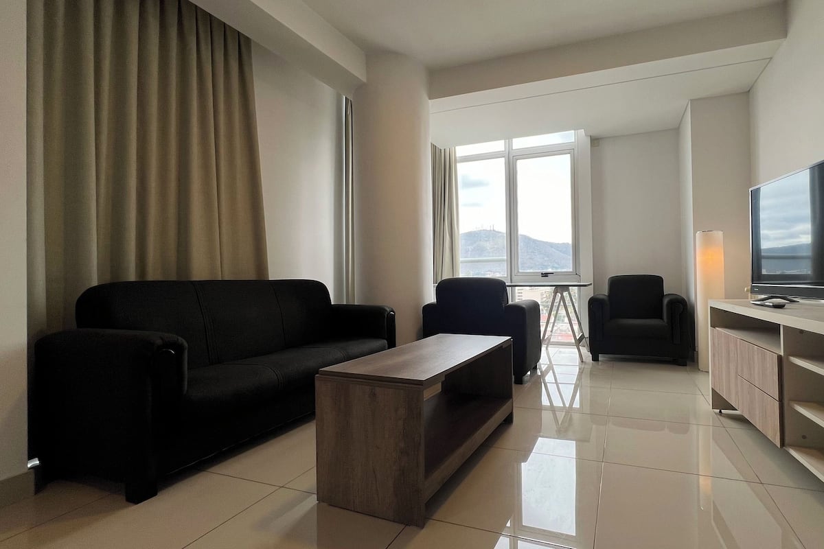 Una sala moderna con un sofá, sillones, una mesa de centro y un televisor.