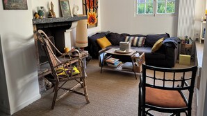 A living room with a fireplace, a sofa, a chair, and a window with curtains.