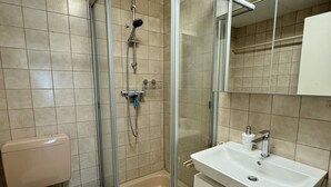 A bathroom with a glass-enclosed shower, a toilet, and a sink with a mirror above it. - H&H Home - Quite and Central Apartment near Park in Sindelfingen (Sindelfingen)