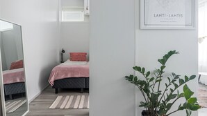 Ein modernes Schlafzimmer mit einem Bett, einem Spiegel, einer Topfpflanze und einer gerahmten Karte an der Wand.