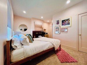 A bedroom with a bed, a bedside table, a mirror, a dresser, and a door.