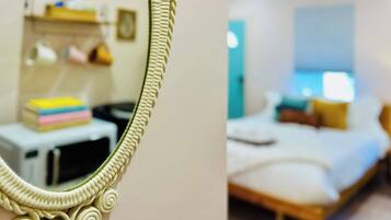 Una habitación con cama, mesita de noche y espejo con marco decorativo.