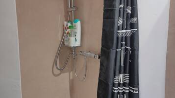 Ein Duschbereich mit Handbrause, Wandarmatur und einer Bedieneinheit für Toilettenartikel.