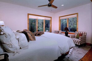 A bedroom with a large bed, two windows, a ceiling fan, and a chair. - Creek Cove, Gorgeous home, hot tub, very private (Crested Butte)
