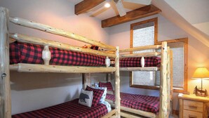 A bunk bed room with a wooden ceiling and a small bedside table with a lamp. - Creek Cove, Gorgeous home, hot tub, very private (Crested Butte)