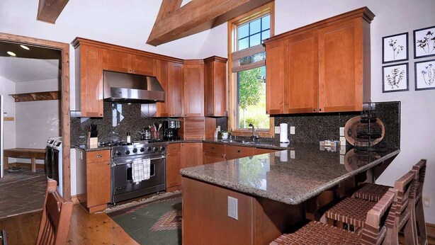 A modern kitchen with wooden cabinets, a central island, and a built-in oven. - Creek Cove, Gorgeous home, hot tub, very private (Crested Butte)
