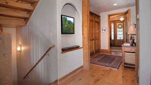A wooden staircase with a handrail, a framed picture on the wall, and a wooden door with a glass panel. - Creek Cove, Gorgeous home, hot tub, very private (Crested Butte)