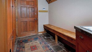 A hallway with a wooden door, a bench, a tiled floor, and a wooden shelf. - Creek Cove, Gorgeous home, hot tub, very private (Crested Butte)