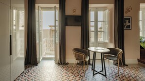 Ein Zimmer mit Fliesenboden, zwei Stühlen, einem kleinen Tisch und einem Fernseher an der Wand.