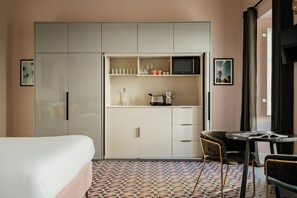 A compact hotel room with a bed, kitchenette, and a small dining area.