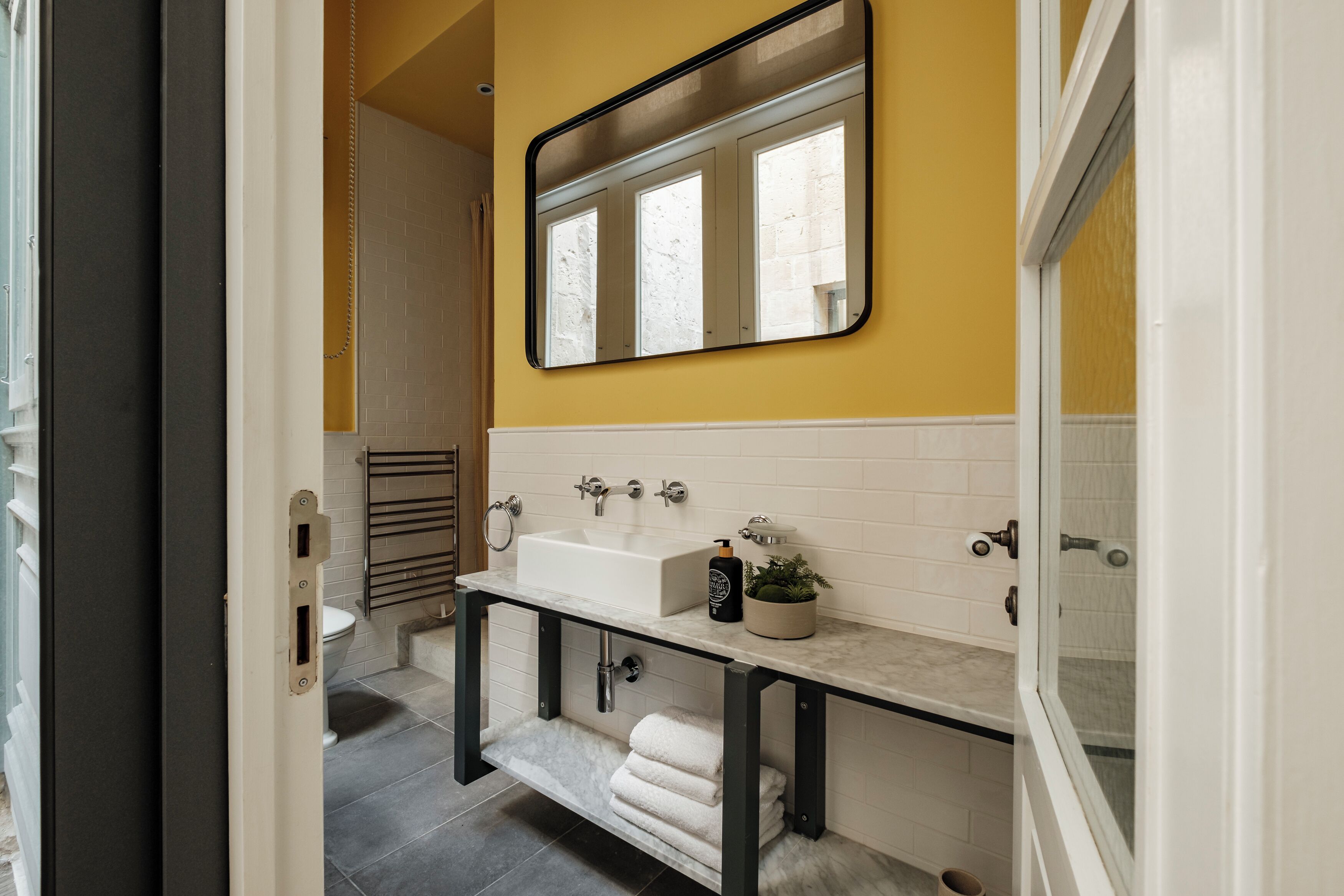 Une salle de bain avec un lavabo blanc, un miroir et un porte-serviettes.