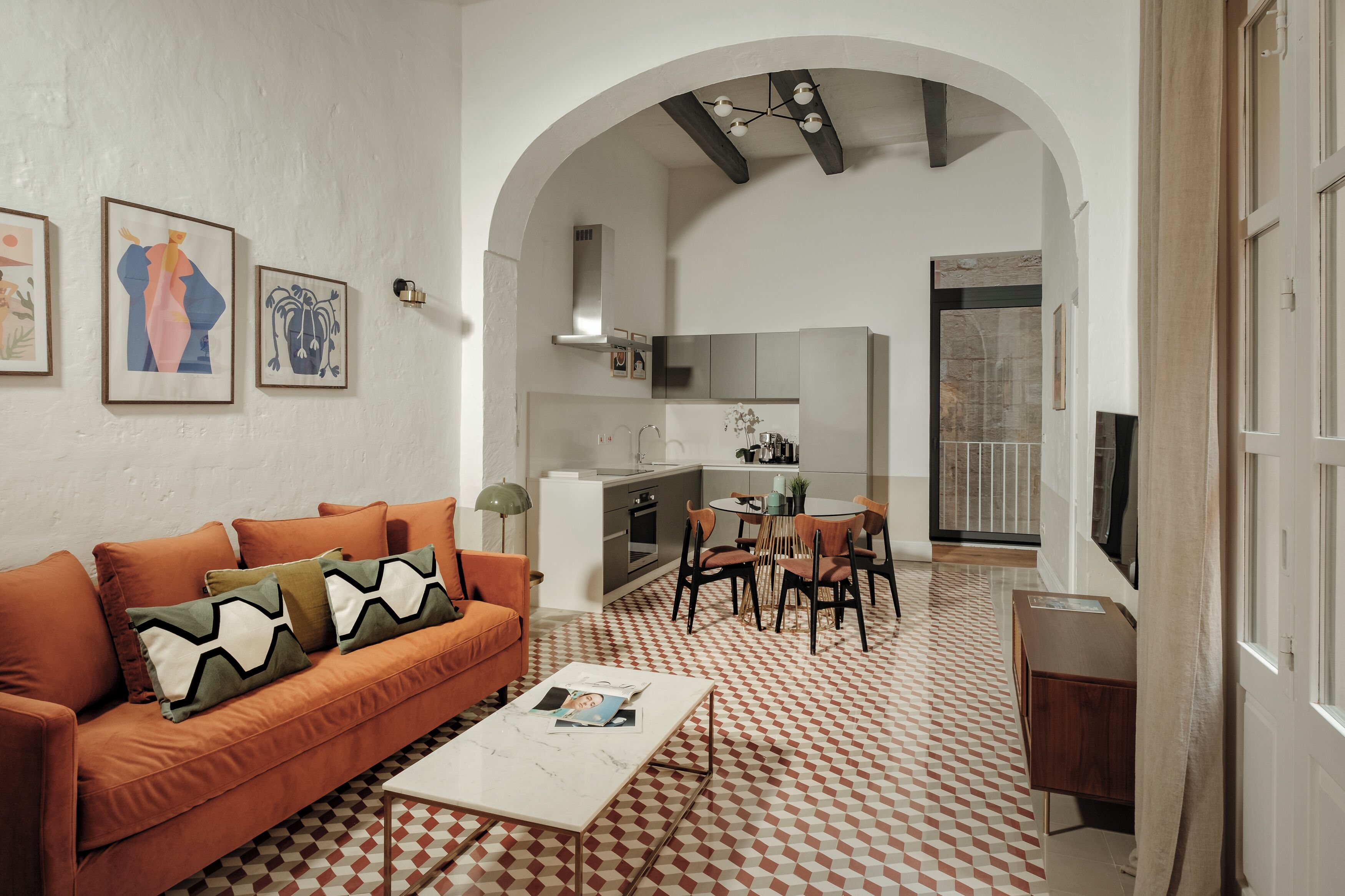 A modern living room with an orange sofa, a coffee table, and a patterned floor.