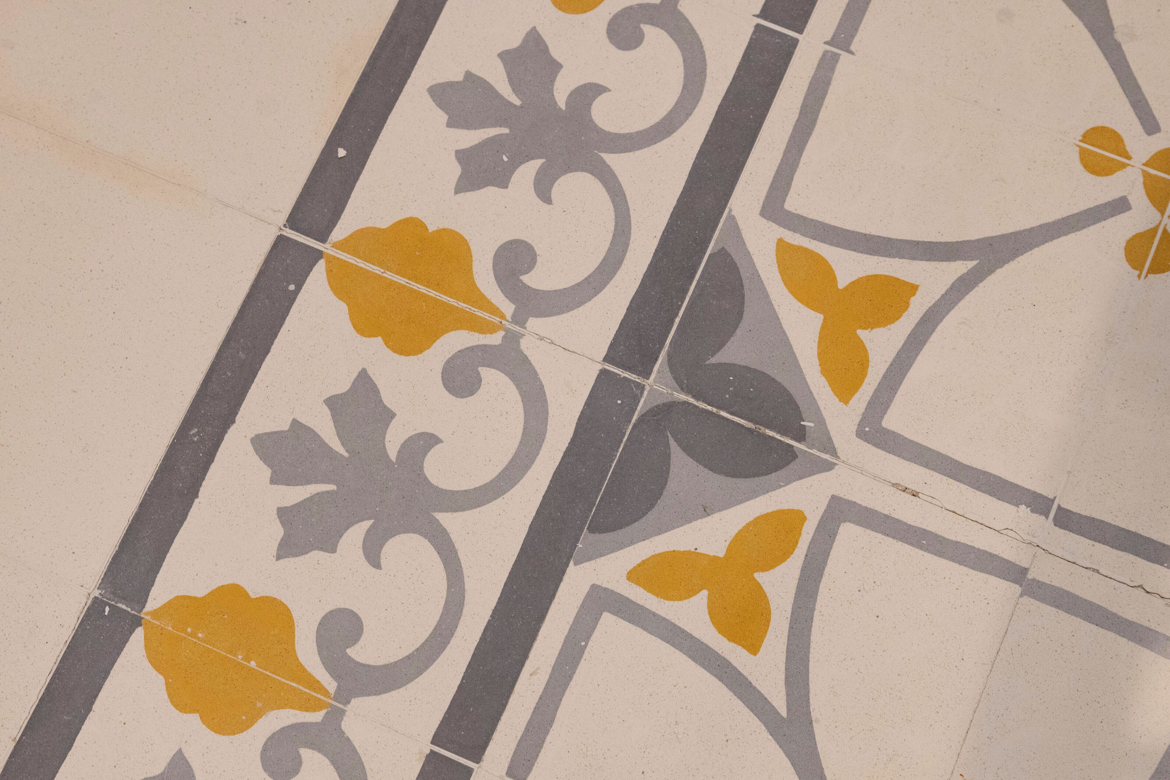 Een close-up van een betegelde vloer met een geometrisch patroon en bloemmotieven.
