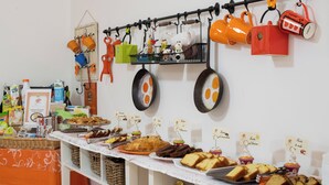 A buffet table with various food items and a wall-mounted rack with kitchen utensils. - Albergo Villa Gaia (Chianciano Terme)