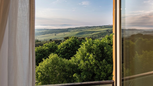 A view from a window overlooking a green landscape with trees and distant hills. - Albergo Villa Gaia (Chianciano Terme)