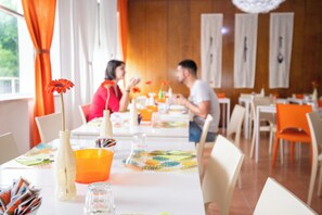 Een restaurant met gedekte tafels, met verschillende tafelopstellingen en een ongedwongen sfeer.