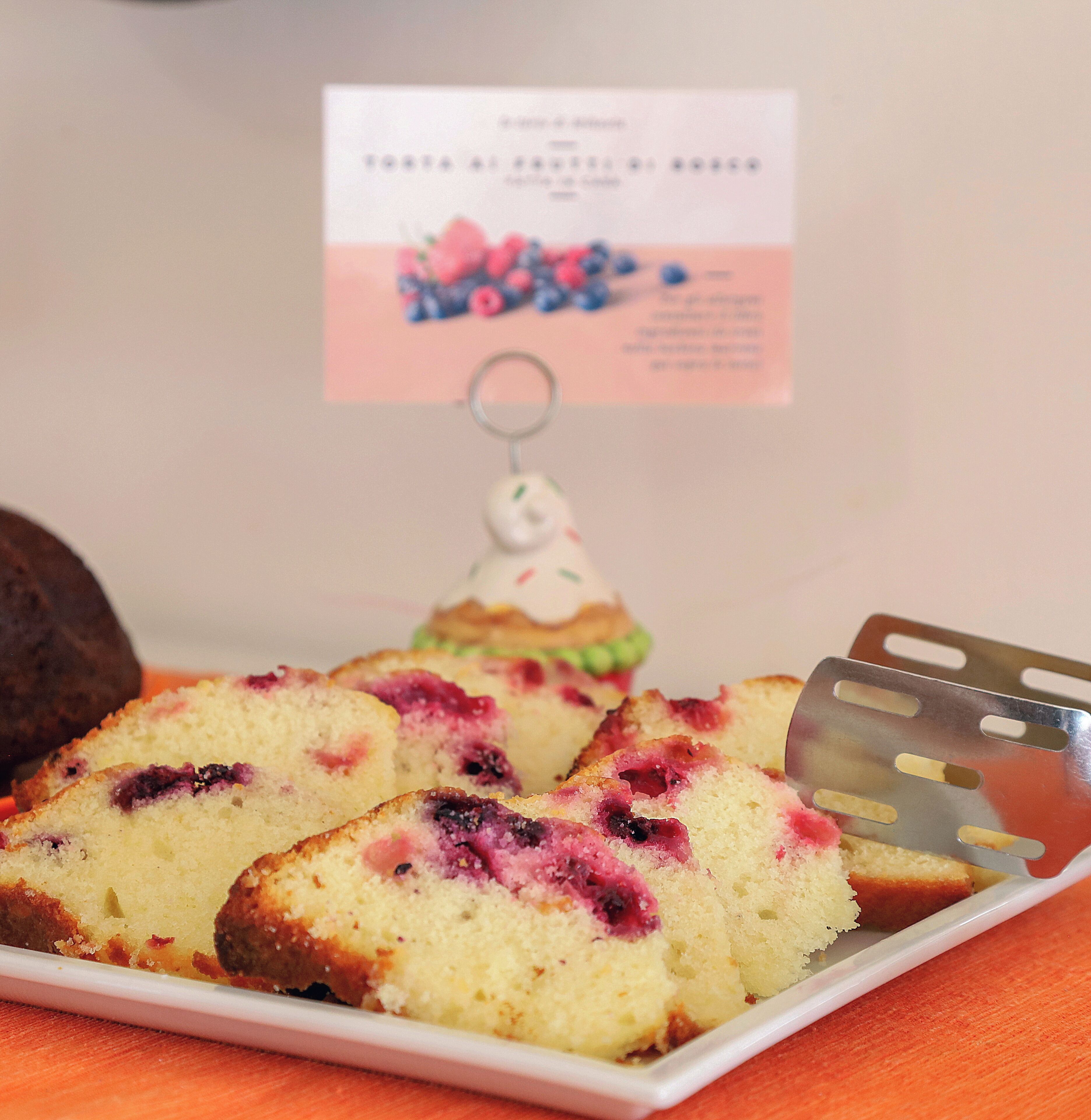 Een bord met blauwe bessen muffins en een kaartje op de achtergrond.