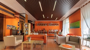 A modern hotel lobby with orange walls, wooden ceiling, and a central seating area with sofas and tables. - Albergo Villa Gaia (Chianciano Terme)