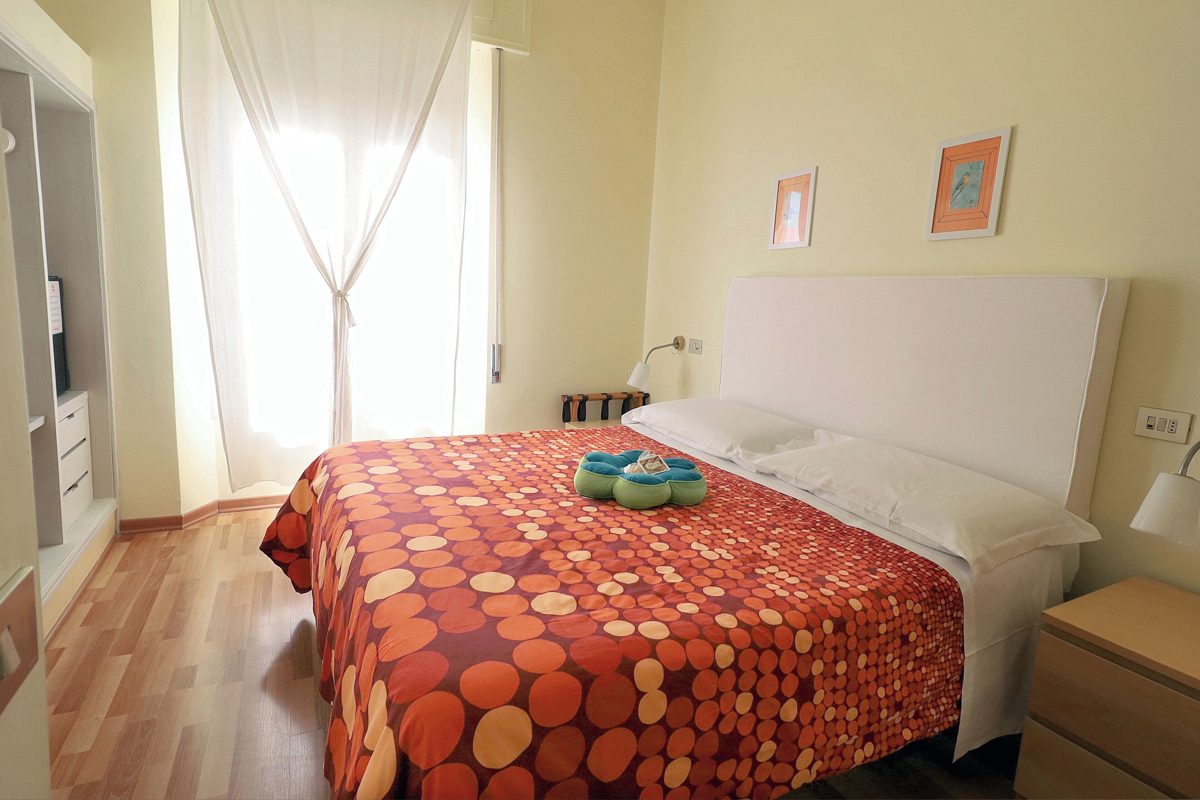 Una habitación de hotel con cama, mesita de noche, lámpara y armario.