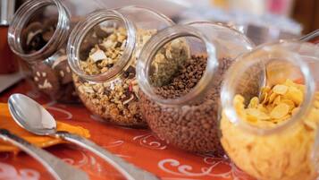 Four glass jars containing different food items on a table with a spoon and a knife.